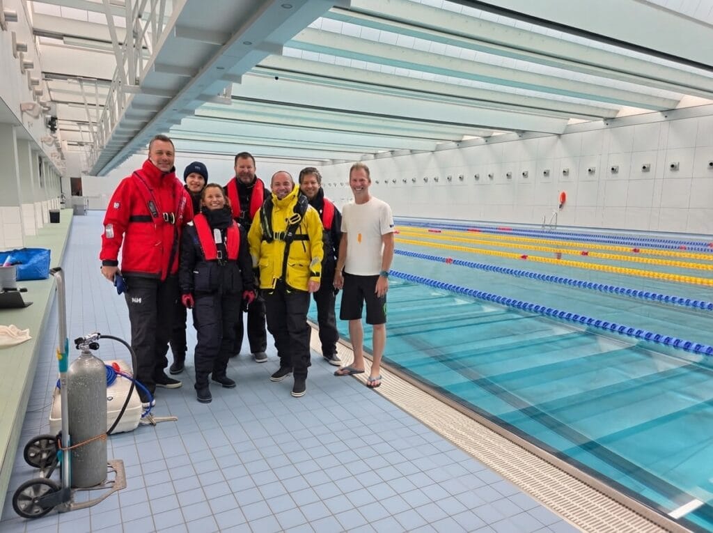 Gruppe des Sea Survival Trainings mit Rettungswesten am Schwimmbecken