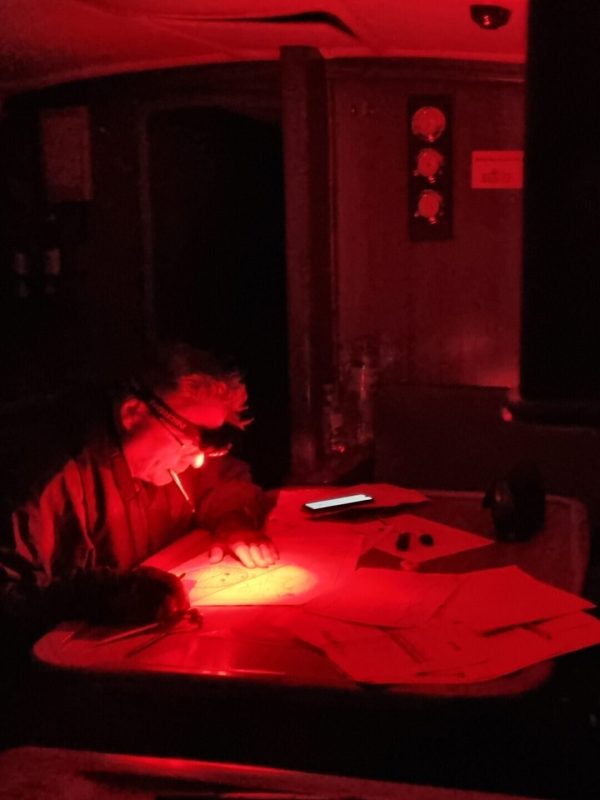 Kartenarbeit bei Nacht an Bord unter Rotlicht
